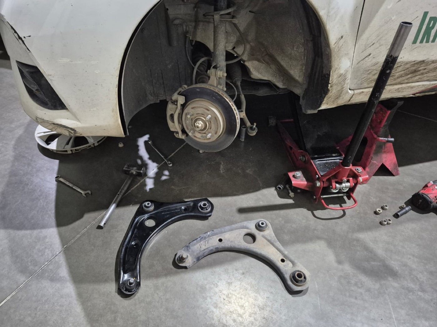 Brazos de suspensión retirados junto al auto en el gato